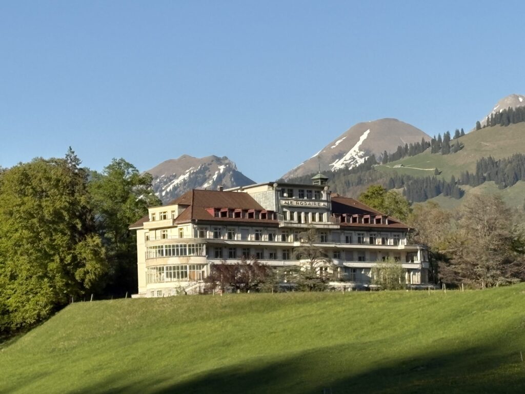 A large hotel building standing in a Swiss alpine meadow
